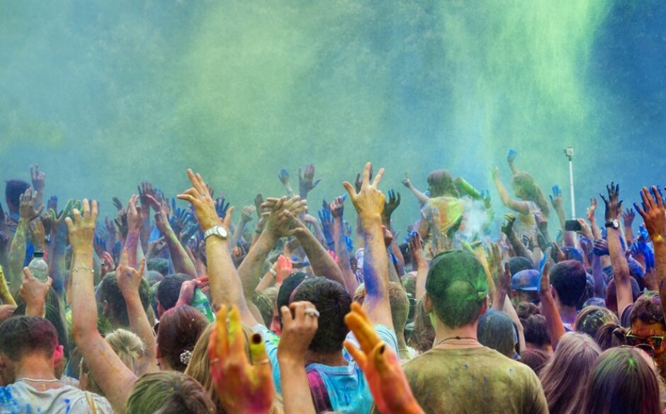 Image of Holi festival - people with arms in the air surrounded by vibrant powder from colourful chalk