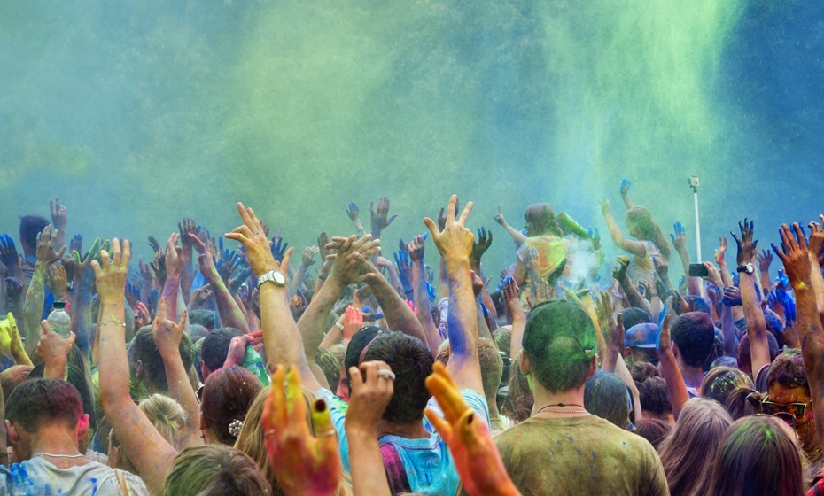 Image of Holi festival - people with arms in the air surrounded by vibrant powder from colourful chalk