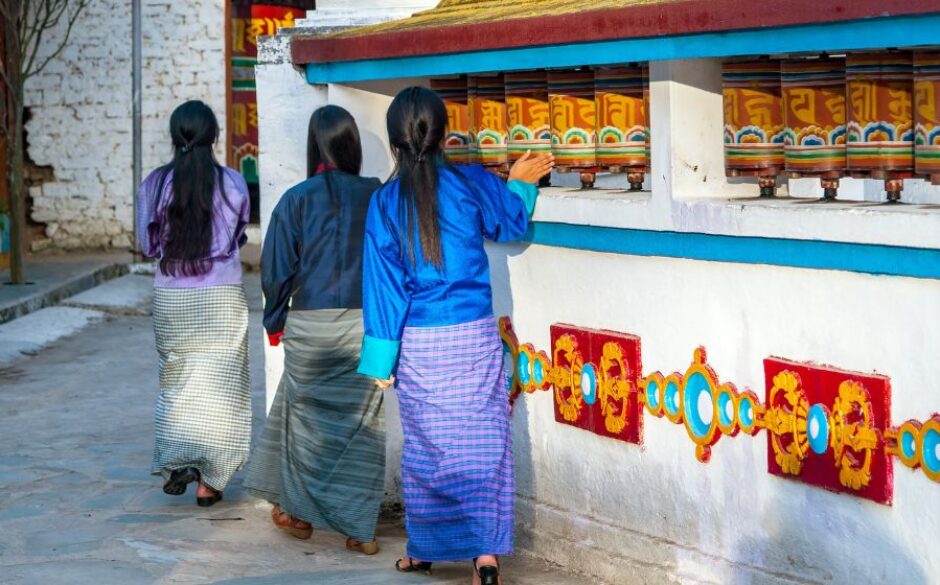 Customs and traditions in Bhutan - Local Bhutanese women turning prayer wheels in a Buddhist temple near Trashigang in Eastern Bhutan