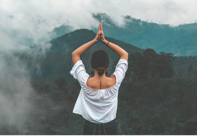 Wellness Retreat in india - woman in a yoga pose on top of a mountain